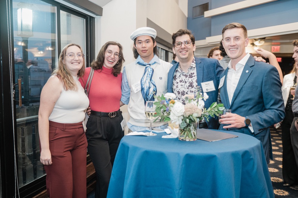 5 GVSU Alumni posed for camera and stand around a table